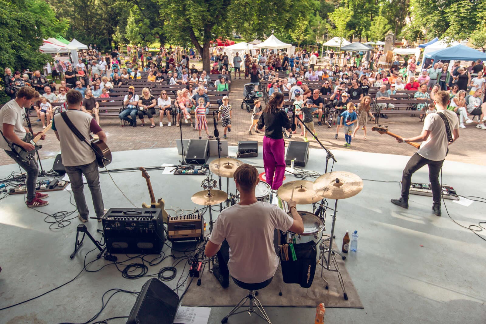 Kapela hraje na pódiu u Mušle v Šanovském parku před davem návštěvníků festivalu Živé Teplice